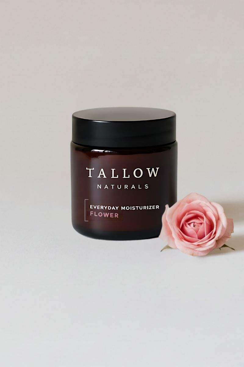 Braune Glasdose mit schwarzem Deckel. Aufschrift: TALLOW NATURALS, EVERYDAY MOISTURIZER FLOWER. Daneben eine rosa Rose.
