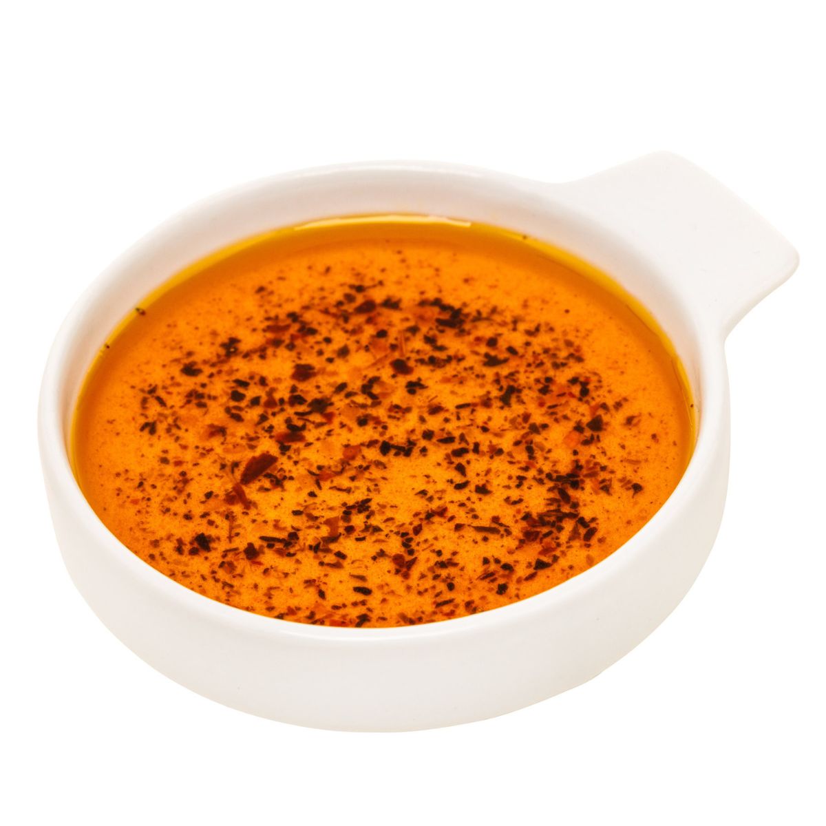 Weiße Schale mit orangefarbener Flüssigkeit, bedeckt mit dunklen Kräutern.