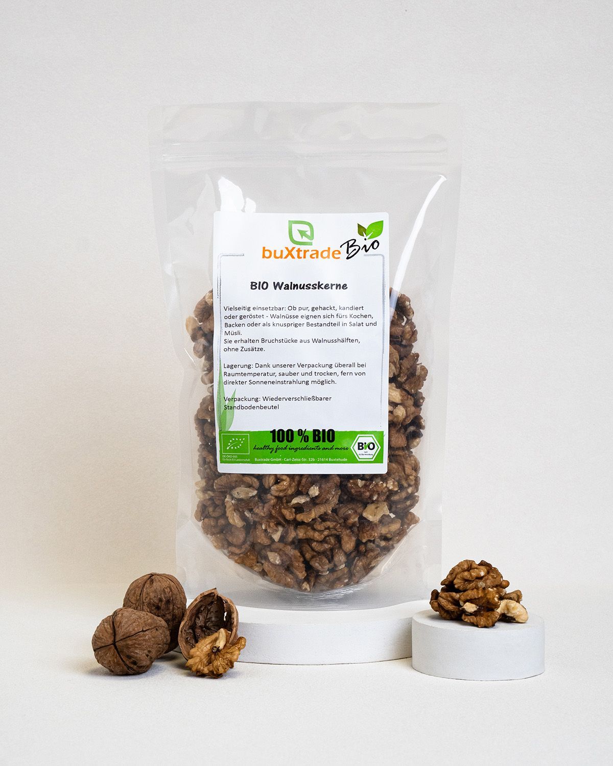 Transparente Verpackung mit Walnusskernen. Etikett mit Produktinformationen und Bio-Siegel. Daneben Walnüsse.