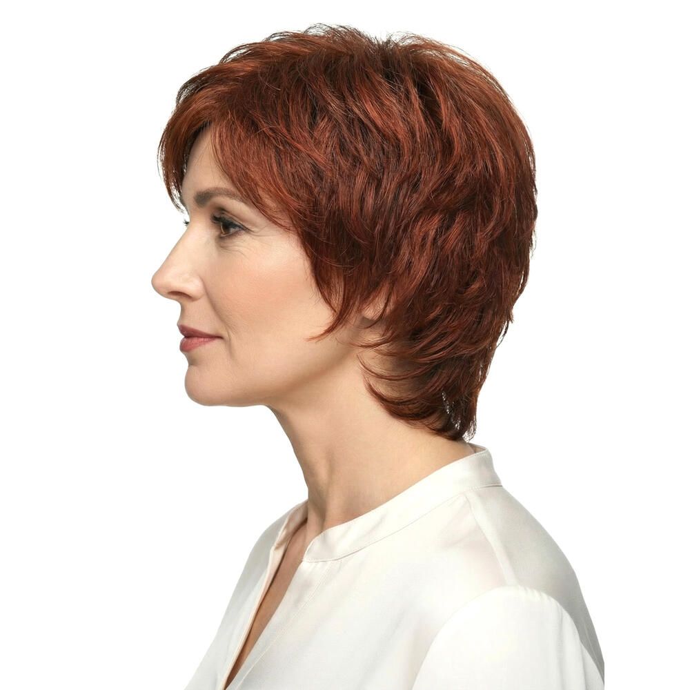 Seitenansicht einer Frau mit rotbrauner Kurzhaarperücke. Sie trägt ein weißes Hemd. Der Blick ist nach links gerichtet.