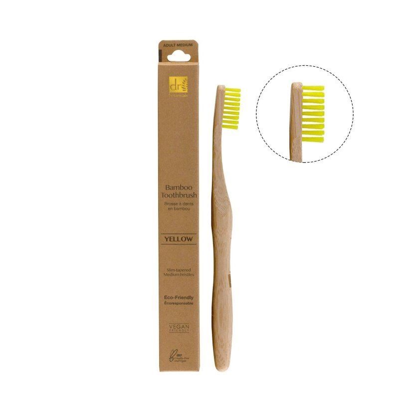 Dr. Botanicals Bambuszahnbürste Gelb mit gelben Borsten und Bambusgriff, neben der Verpackung.