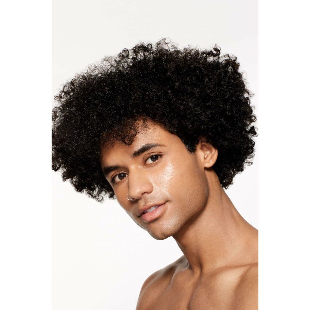 Porträt eines Mannes mit lockigem Haar. Haut mit Foundation. Blick in die Kamera.