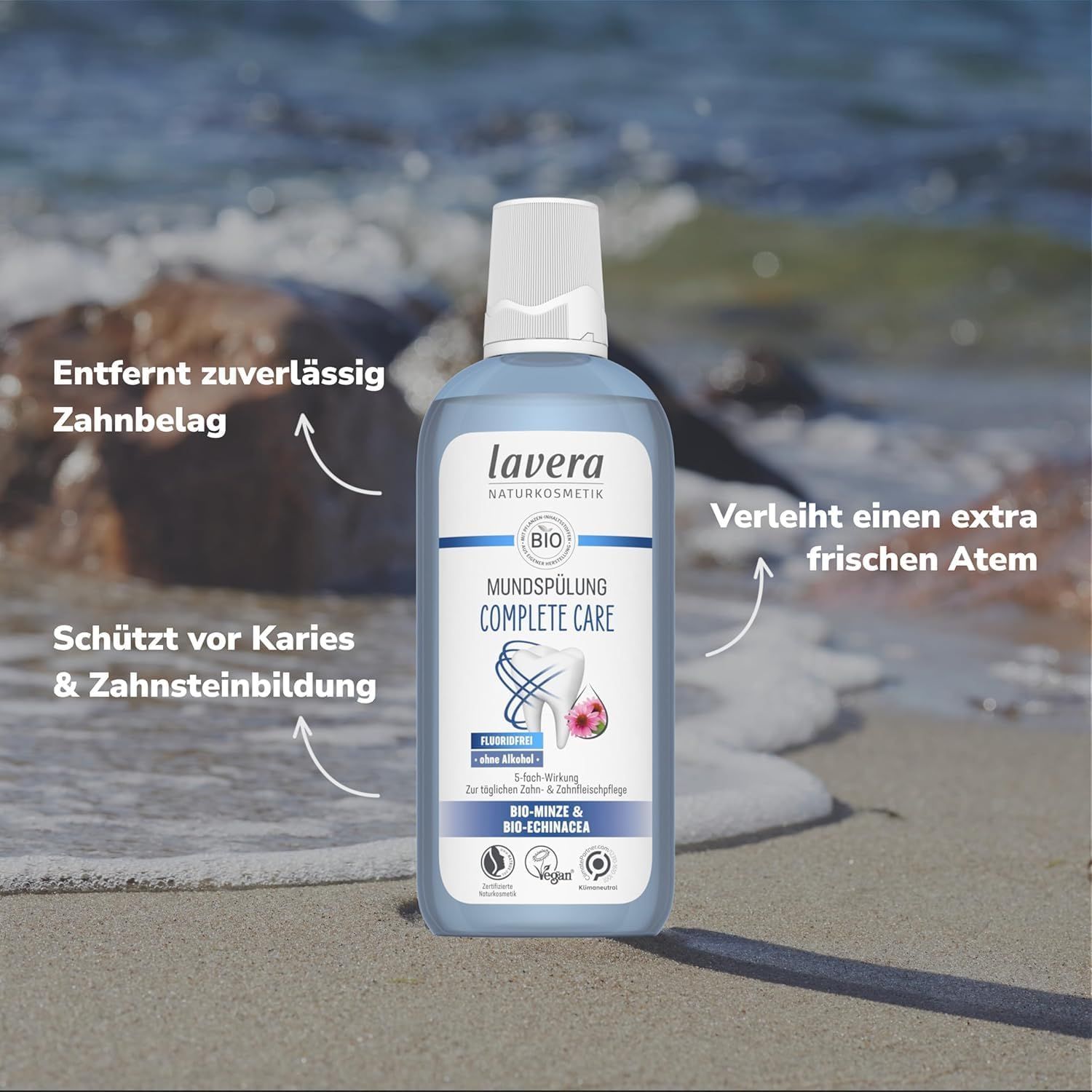 Blaue Flasche Mundspülung lavera am Strand. Text: Schützt vor Karies, verleiht frischen Atem. Vegan-Siegel.