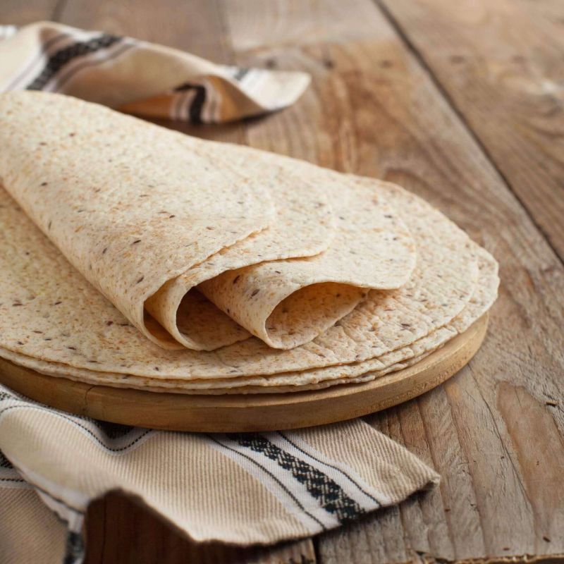 Drei gefüllte Wraps auf einem Jutegewebe. Mit Papier umwickelt und mit Schnur gebunden.
