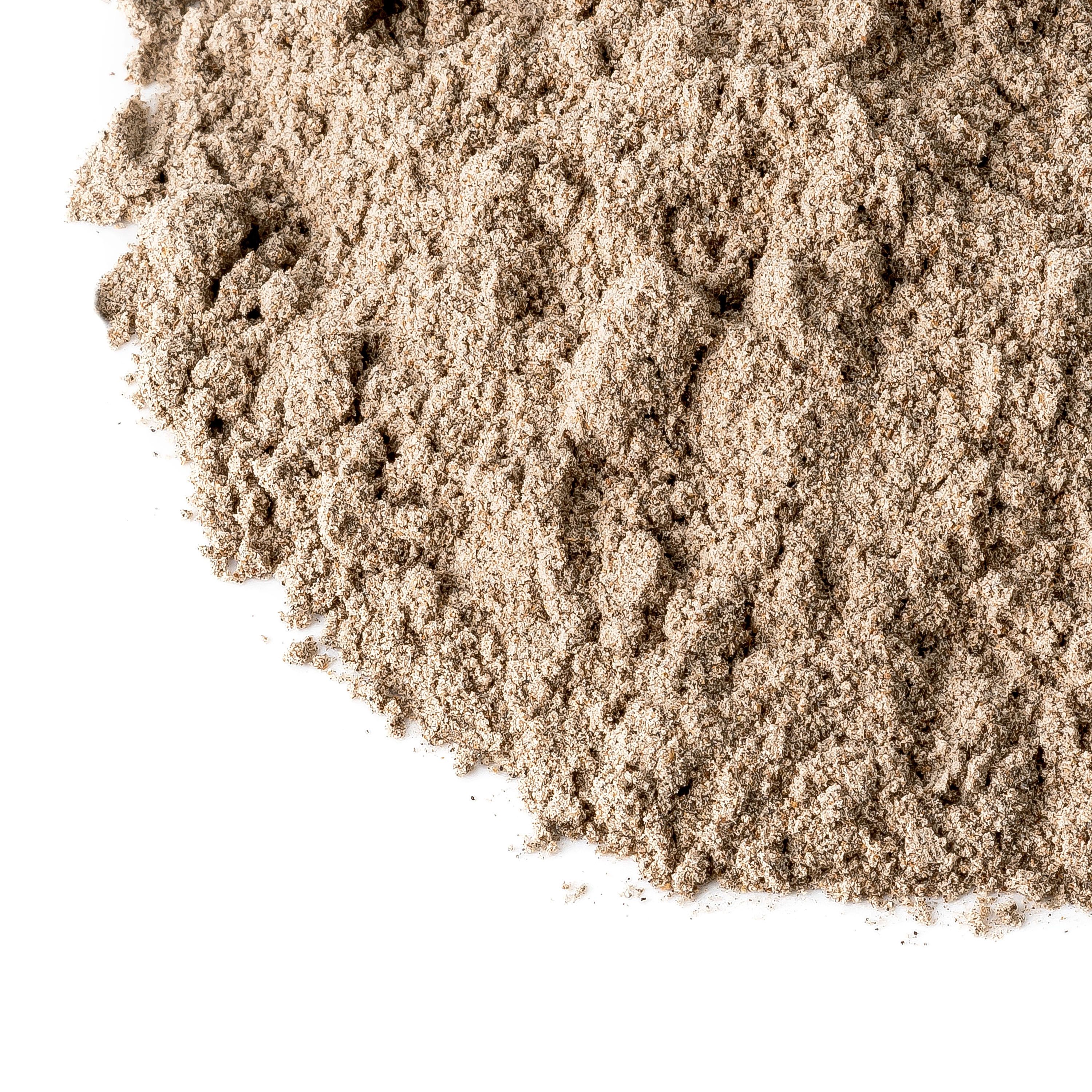 Gemahlene Kardamom-Saat. Nahaufnahme von braunem Pulver. Weißer Hintergrund. Keine Verpackung sichtbar.