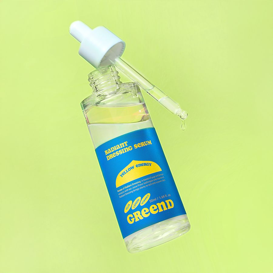 Geöffnete Glasflasche mit Pipette. Blaues Etikett mit "Radiant Dressing Serum" und "greend". Gelbe Flüssigkeit.