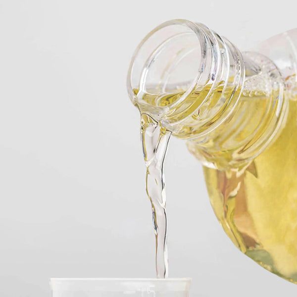 Flüssigkeit wird aus einer Flasche in einen Becher gegossen. Klare Flüssigkeit.