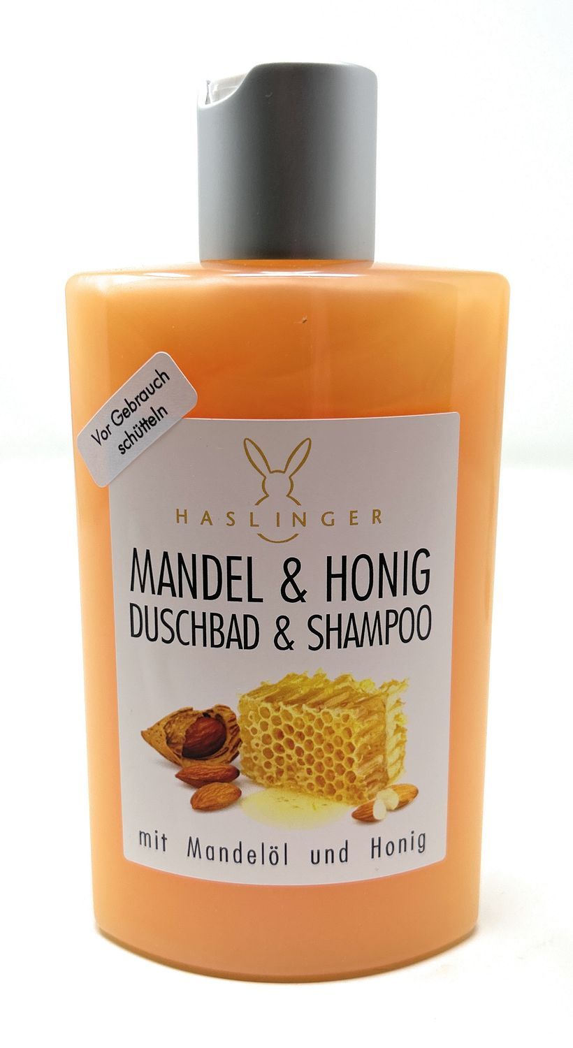 Orangefarbene Flasche mit grauem Deckel. Aufkleber mit Produktnamen: Mandel & Honig Duschbad & Shampoo. Haslinger-Logo.