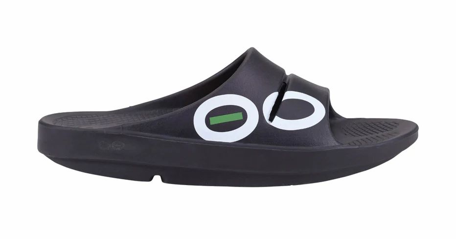 Schwarze Sport-Badesandale mit weißem Logo. Seitliche Ansicht. OOFOS-Schriftzug. Geformtes Fußbett. Riemen über dem Spann.