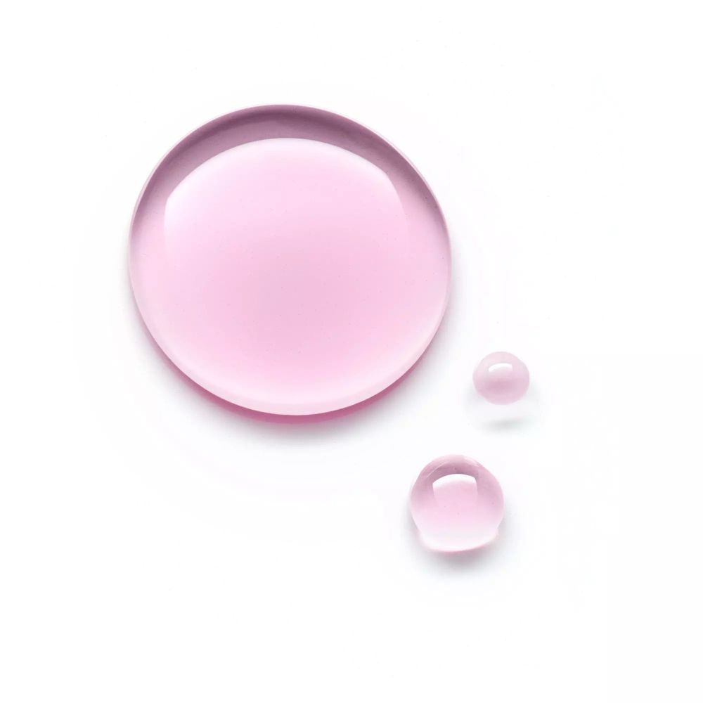 Drei rosa Flüssigkeitstropfen auf weißem Hintergrund. Runde Form, unterschiedliche Größen.