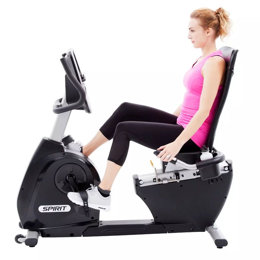 Frau sitzt auf einem Ergometer. Sie trägt Sportkleidung. Das Gerät hat ein digitales Display und die Marke Spirit.