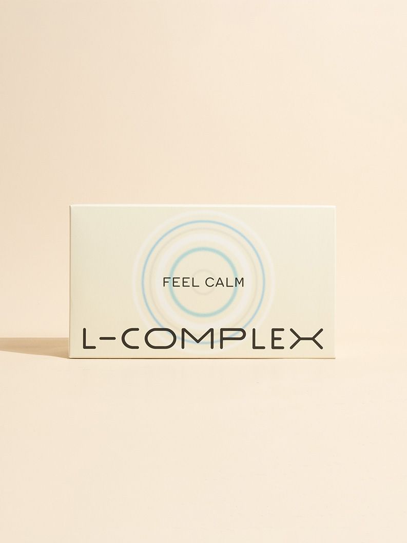 Karton mit Aufschrift L-COMPLEX FEEL CALM. Blau-weiße Kreise als Designelement. Rechteckige Form, cremefarbener Hintergrund.
