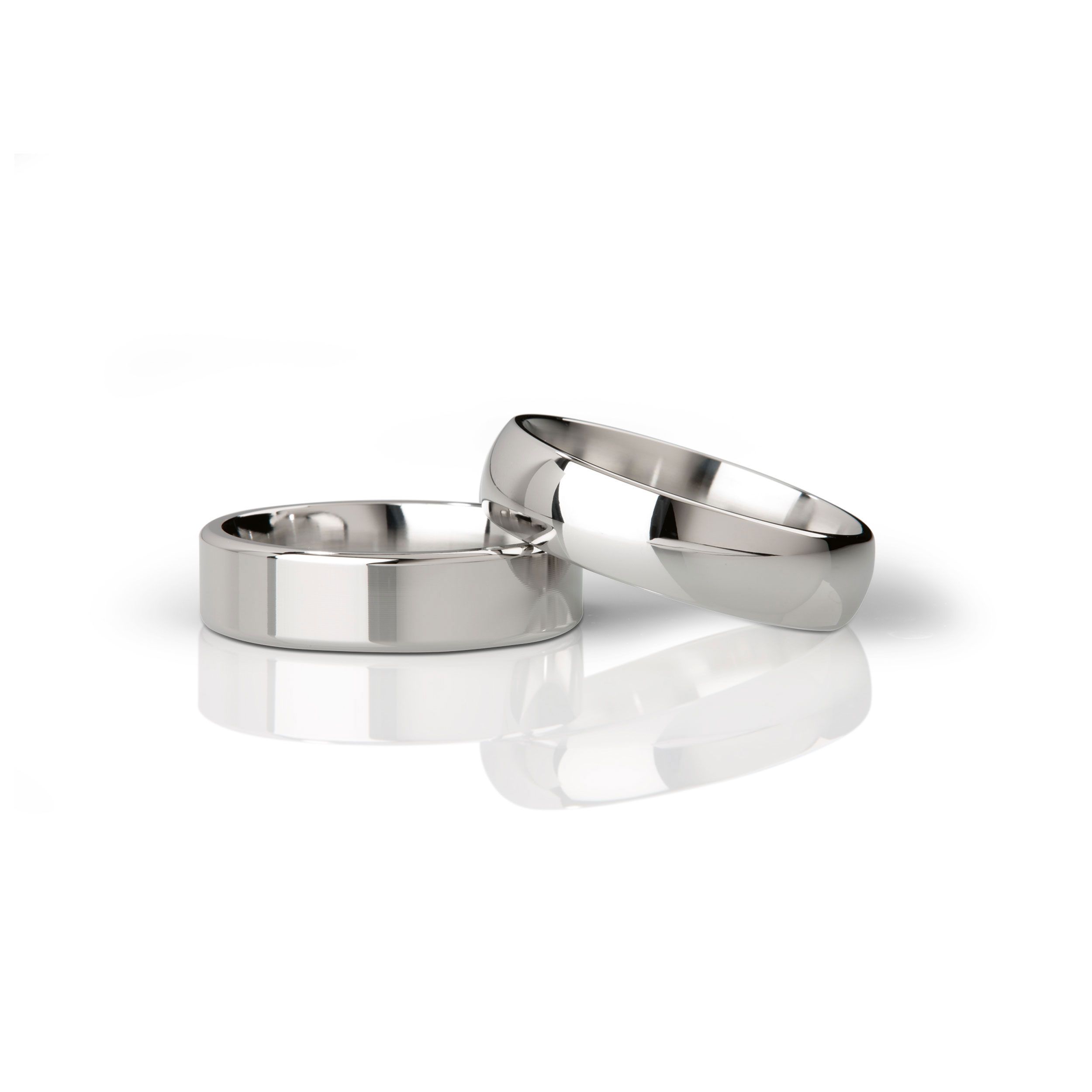 Zwei polierte Metallringe. Ein Ring flach, der andere gewölbt. Auf weißem Hintergrund.