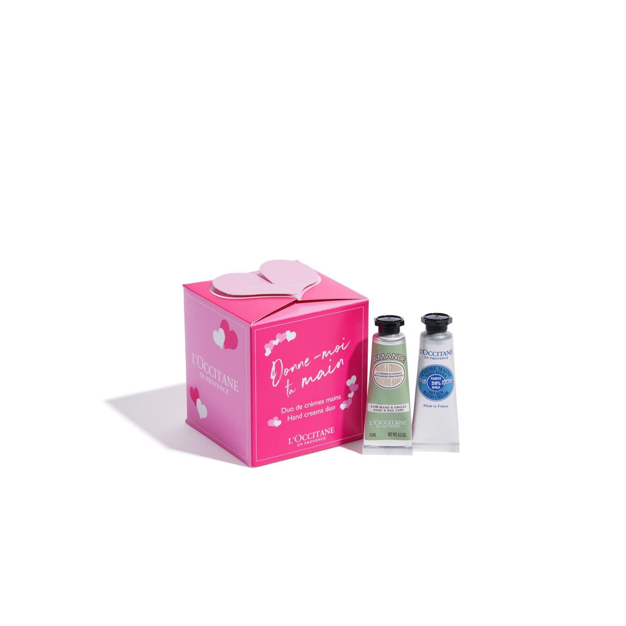 Rosa Geschenkbox mit Herzdeckel. Zwei Handcremes neben der Box. Auf der Box steht "Donne-moi t main" und "L'Occitane".