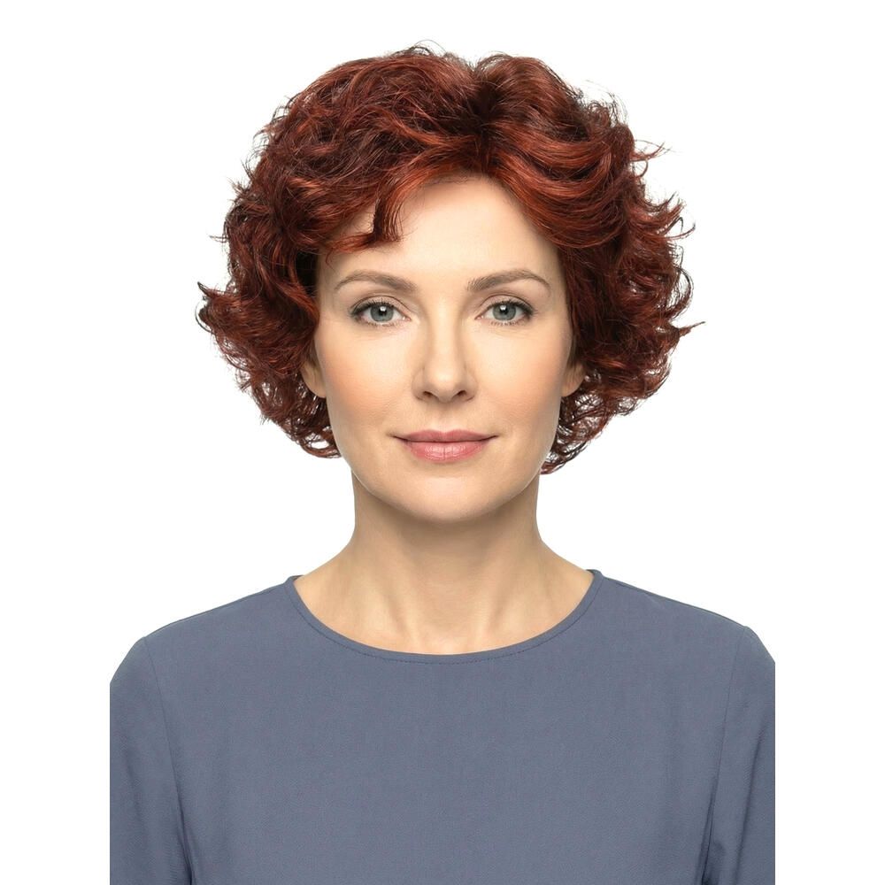 Frau mit roter, lockiger Perücke. Frontalansicht. Kurzes, voluminöses Haar. Bluse in Blau. Weißer Hintergrund.