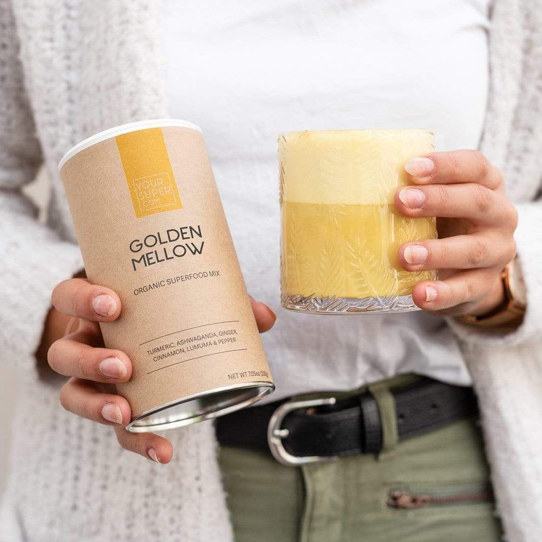 Person hält Dose und Glas mit gelbem Getränk. Dose: 'Golden Mellow'. Glas: gelbes Getränk.
