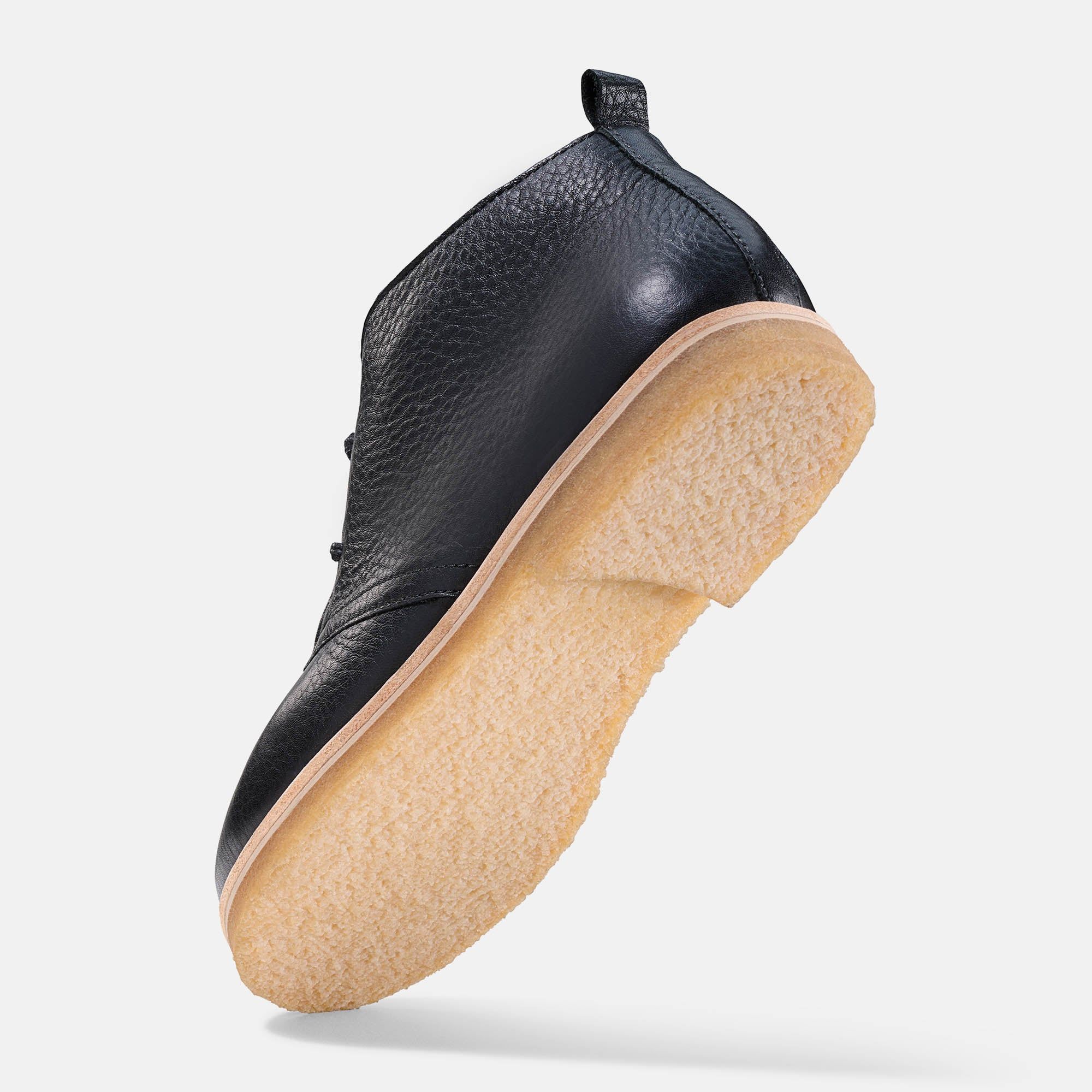 Schwarzer Stiefelette mit heller Sohle. Lederstruktur sichtbar. Ansicht von unten.
