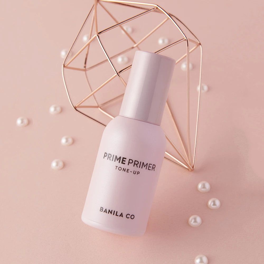 Rosa Primer-Flasche mit Deckel. Aufschrift: PRIME PRIMER TONE-UP, BANILA CO. Dekoration mit Perlen und goldener Form.