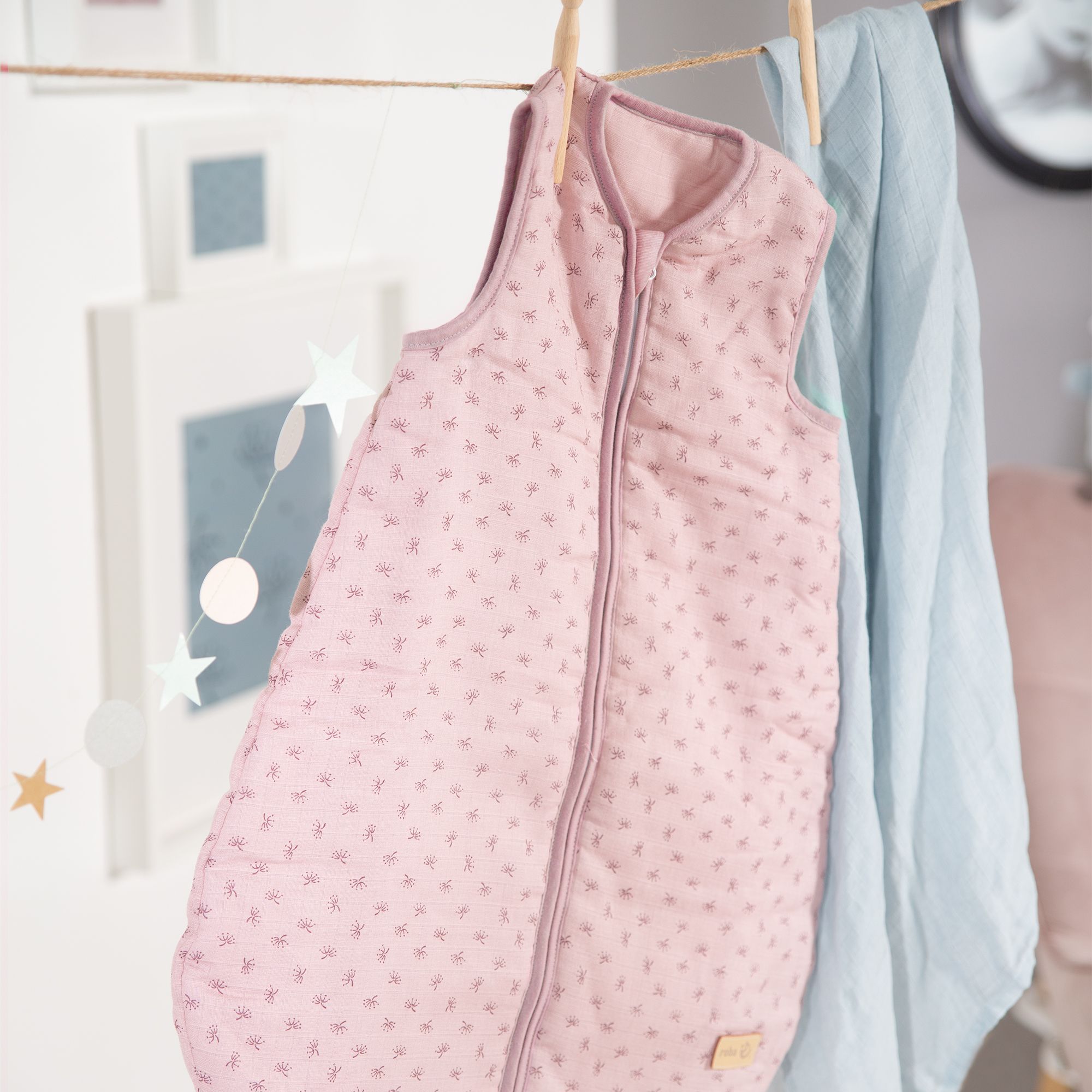 Rosa Schlafsack mit Reißverschluss und Blumenmuster, an einer Wäscheleine aufgehängt.