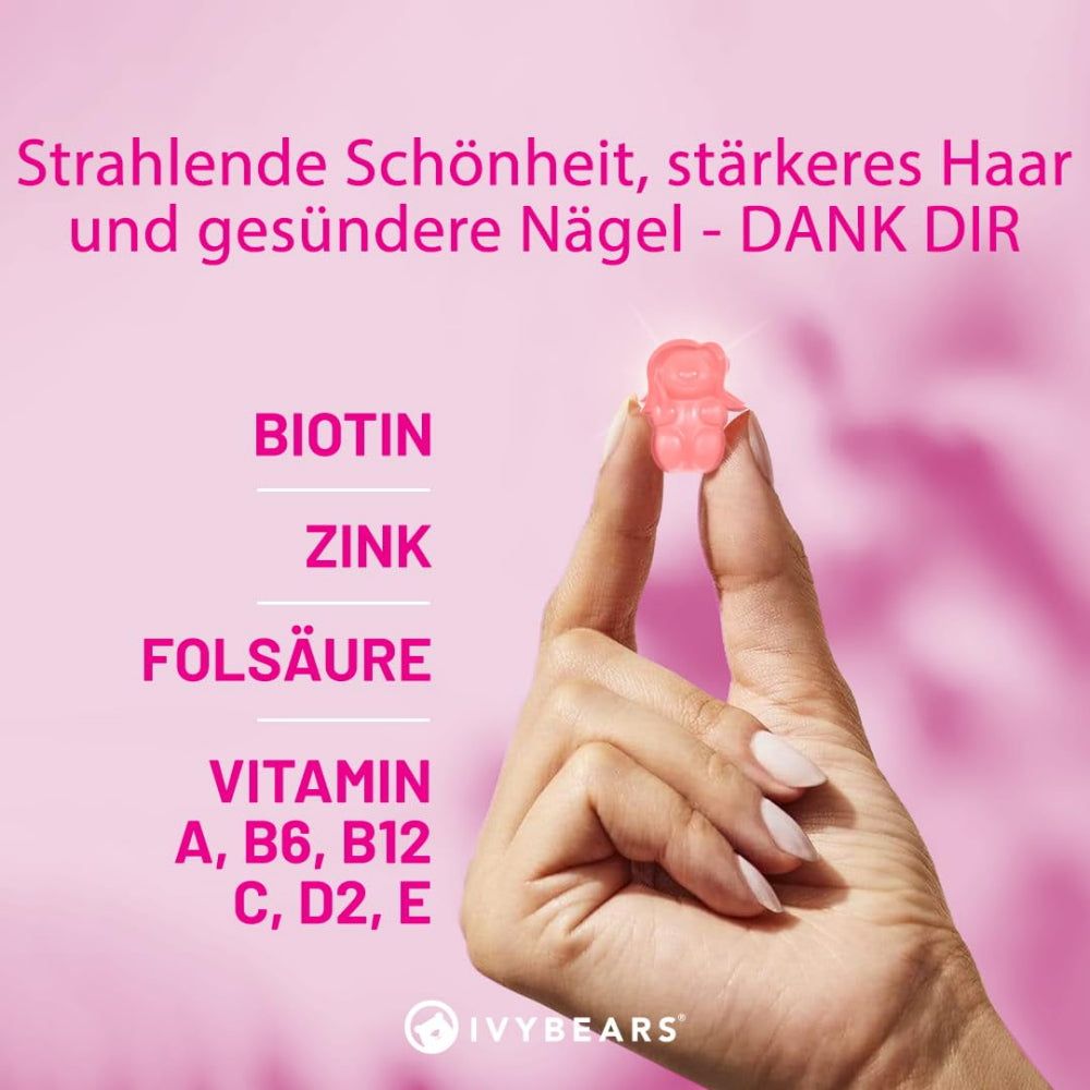 Hand hält rosa Gummibärchen. Aufschrift: Biotin, Zink, Folsäure, Vitamin A, B6, B12, C, D2, E.