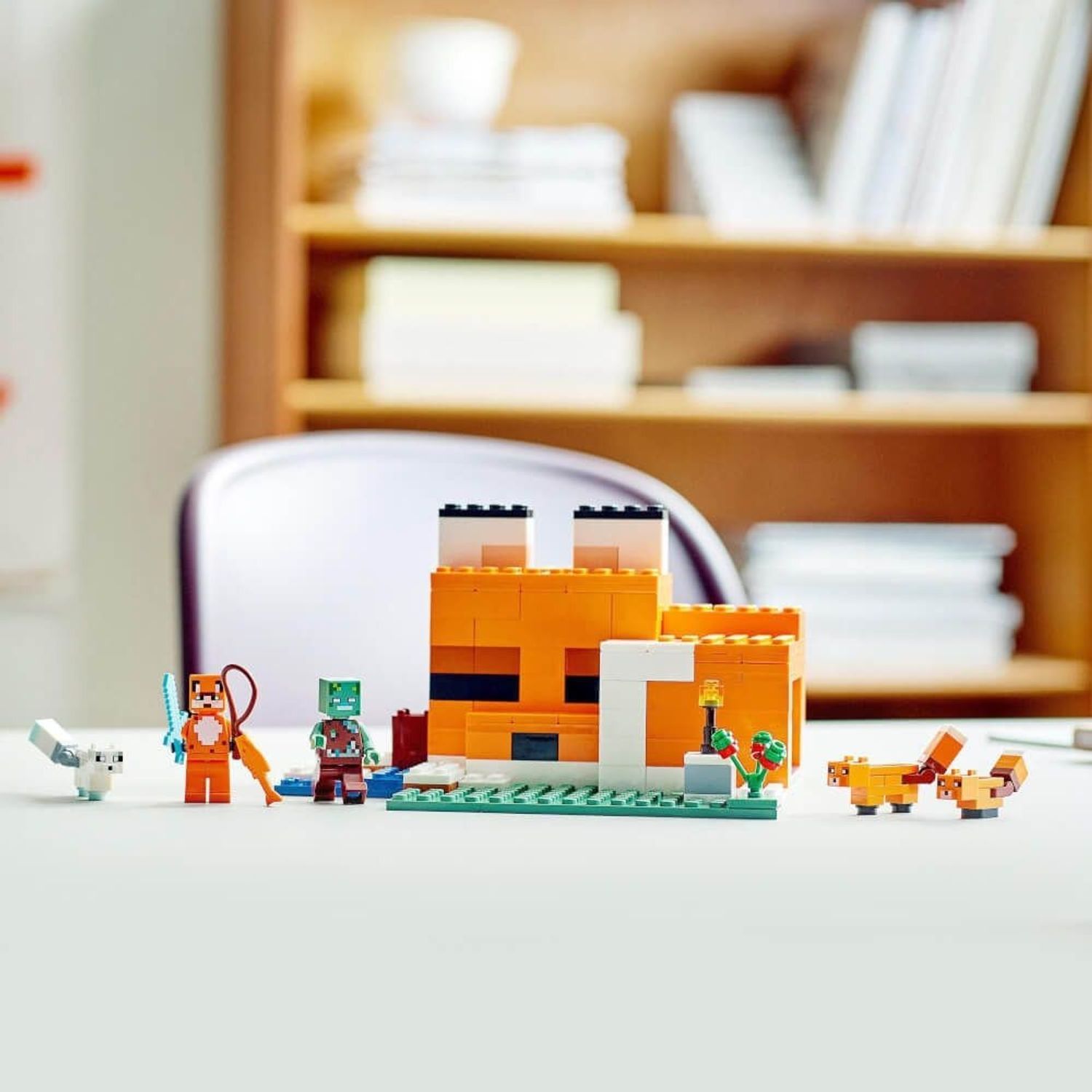 LEGO Minecraft 21178. Orangefarbenes Gebäude mit weißen Akzenten. Figuren: Fuchs, Zombie, Füchse, weißer Fuchs. Auf Tisch platziert.