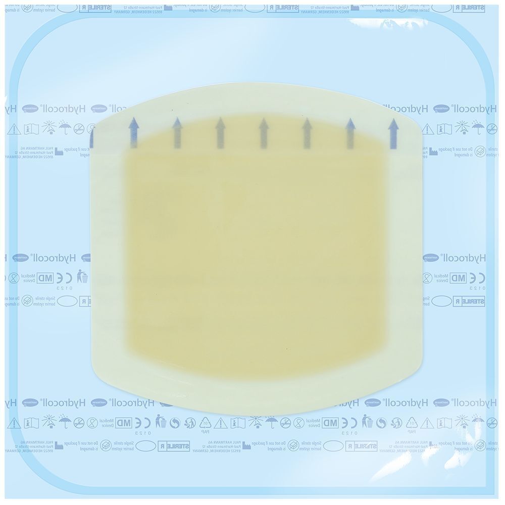 Verband im Beutel. Rechteckige Form, gelbliche Farbe. Pfeile zeigen die Anwendungsrichtung an. Aufschrift: Hydrocoll.