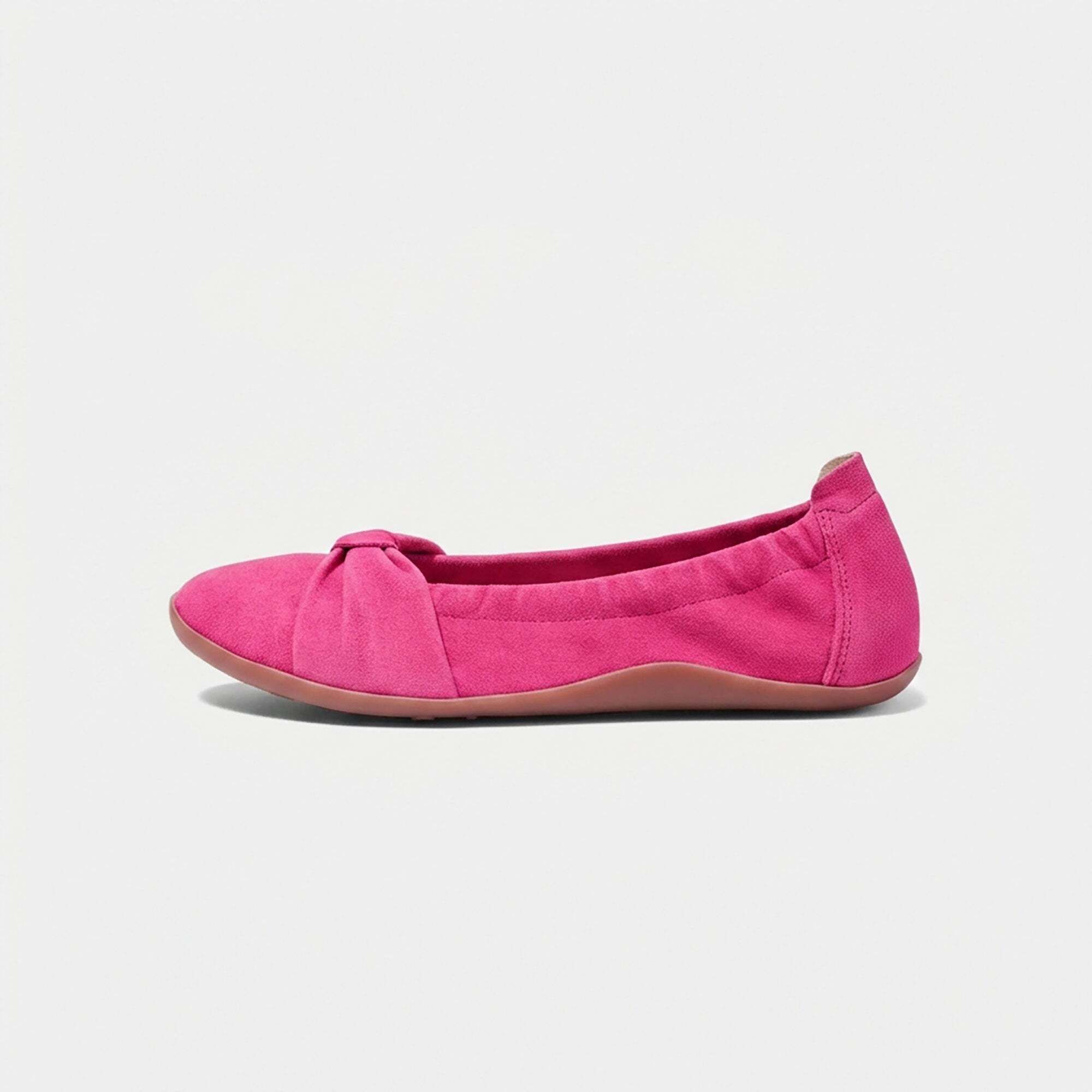 Eine pinke Ballerina aus Wildleder mit Schleifen-Detail und Gummizug, Seitenansicht.