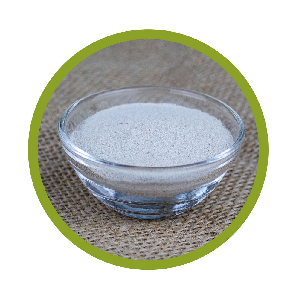 Runde, grüne Umrandung. Glasschale mit weißem Pulver auf grobem Stoffhintergrund.