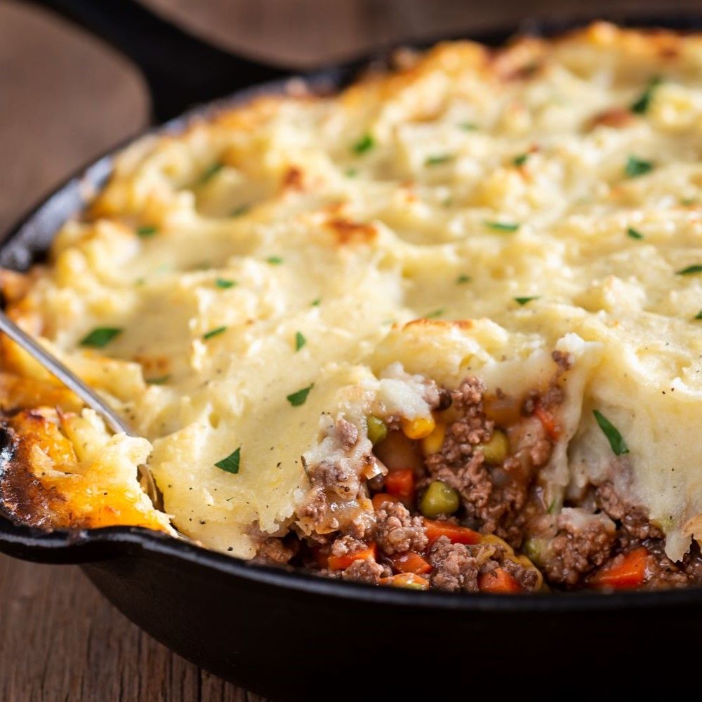 Schäferkuchen in schwarzer Pfanne. Hackfleisch, Gemüse, Kartoffelpüree. Löffel in der Pfanne.