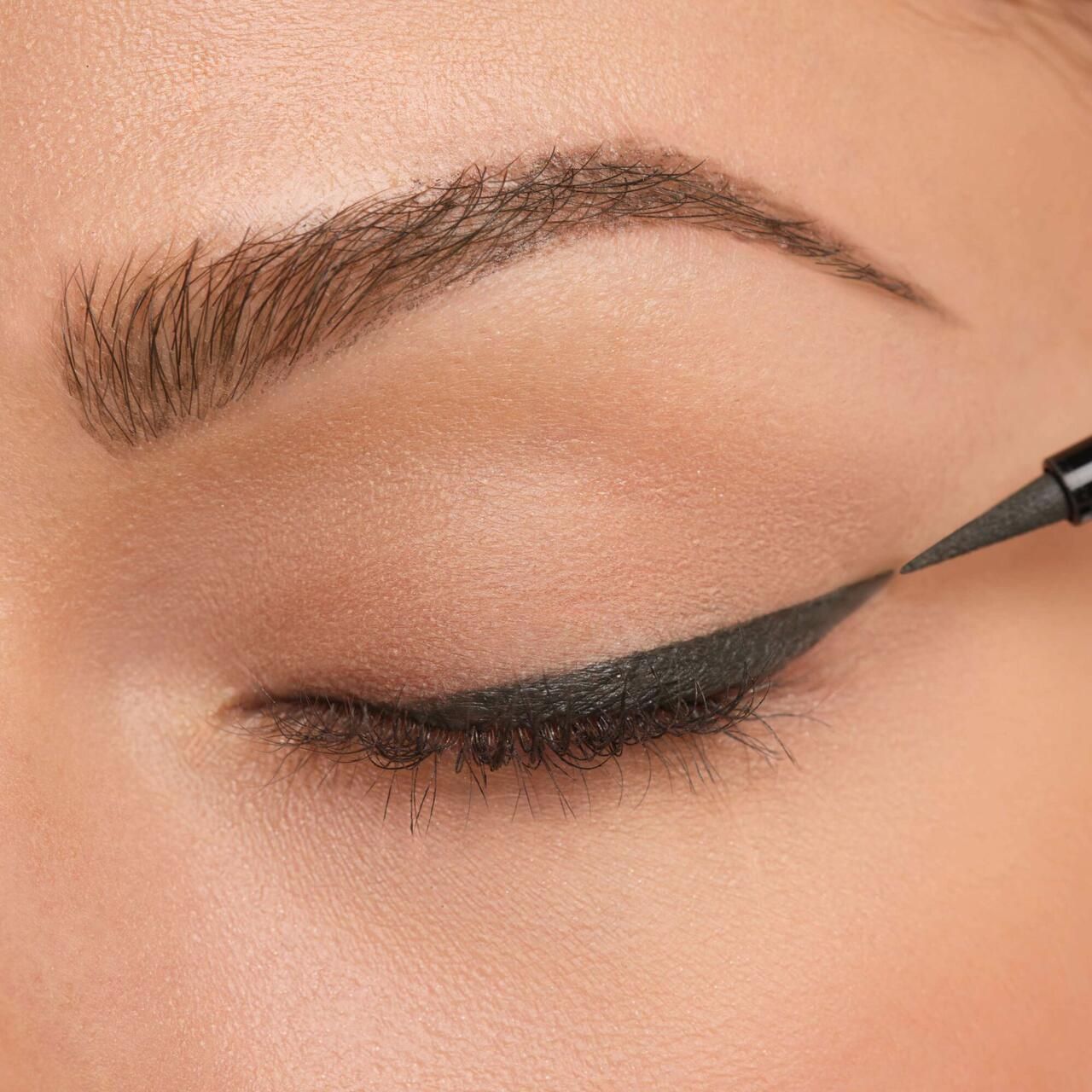 Auge mit aufgetragenem schwarzem Eyeliner. Eyeliner wird auf das Augenlid aufgetragen.