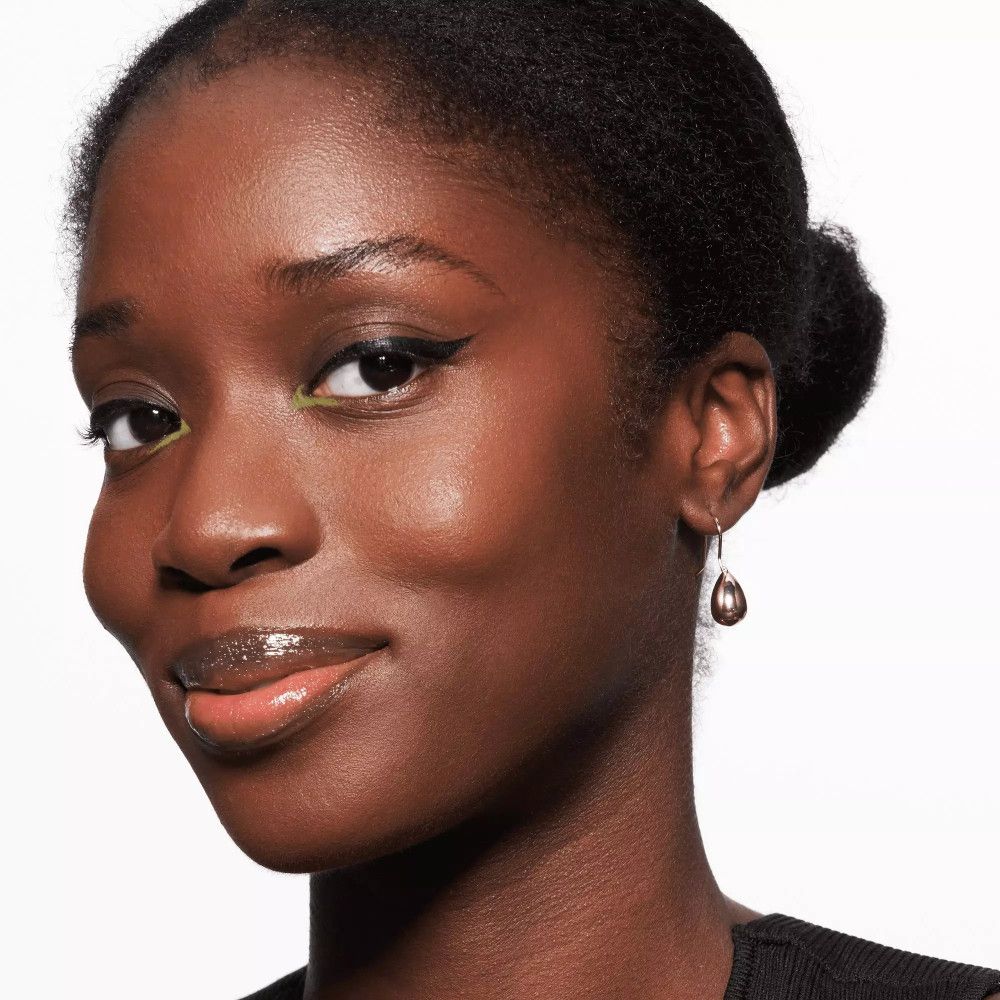 Porträt einer Frau mit Kajal auf den Augenlidern. Dunkle Haut, Dutt, Ohrringe.