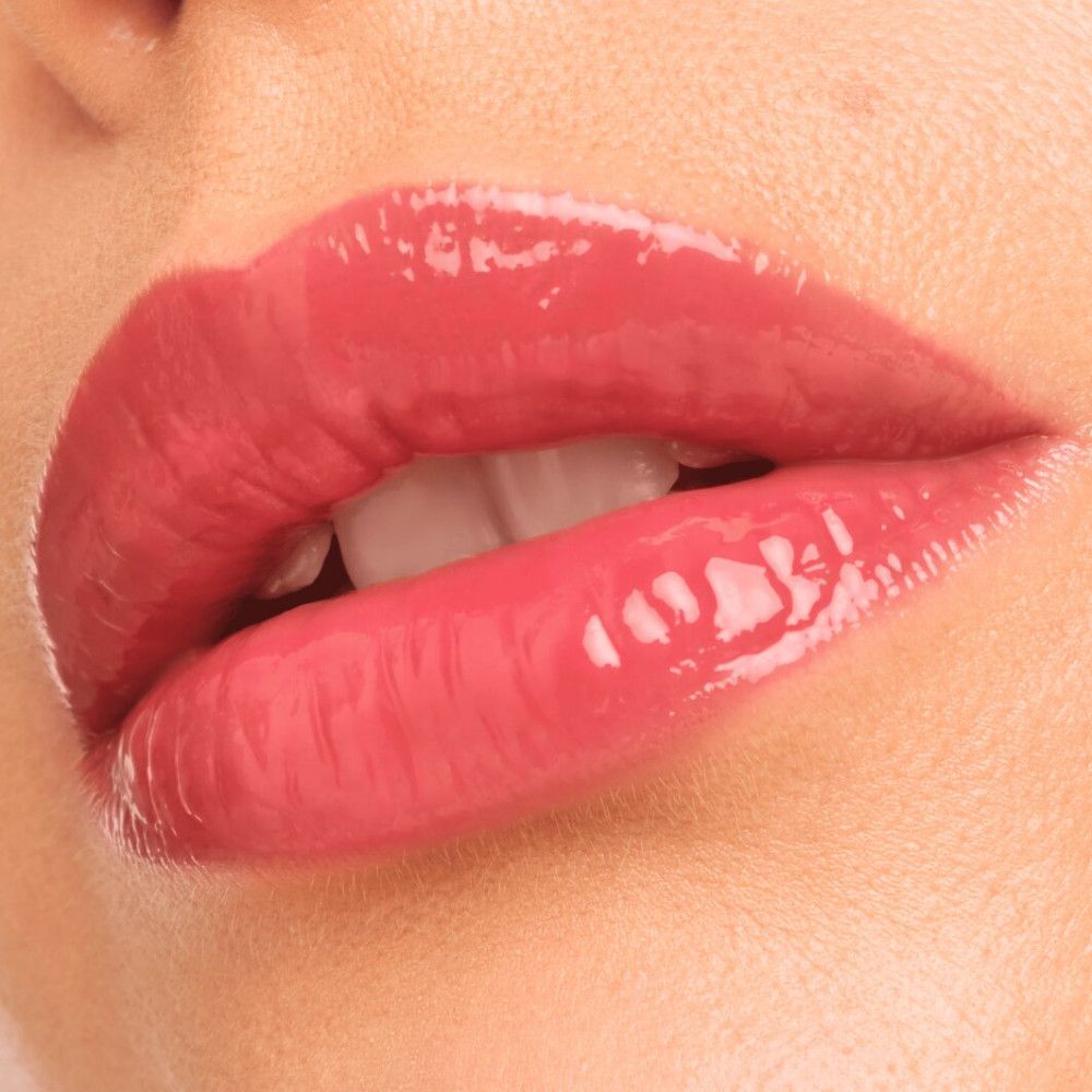 Nahaufnahme von Lippen mit aufgetragenem rosa Glanz. Glänzende Oberfläche. Sichtbare Zähne.