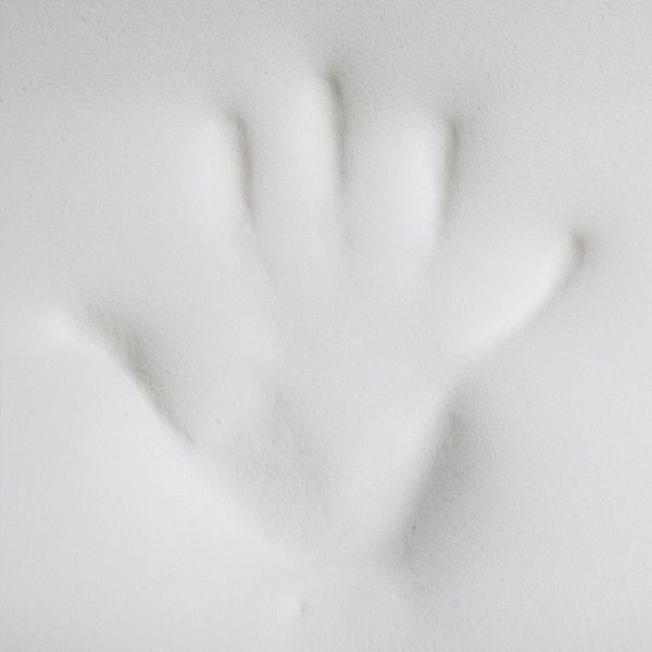 Nahaufnahme eines weißen Memory-Foam-Kissens mit Handabdruck.