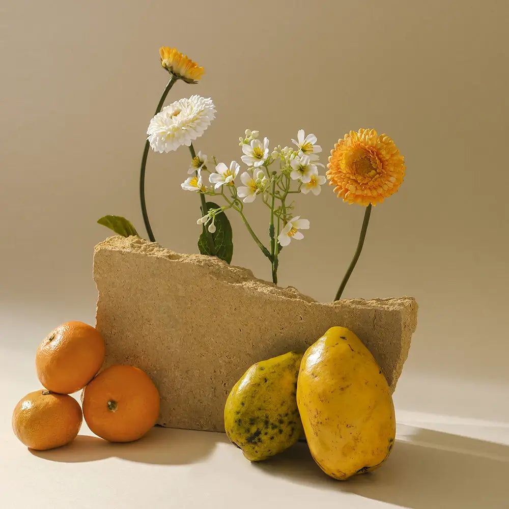 Ein Steinblock mit Blumen und Früchten: Mandarinen und Papayas.