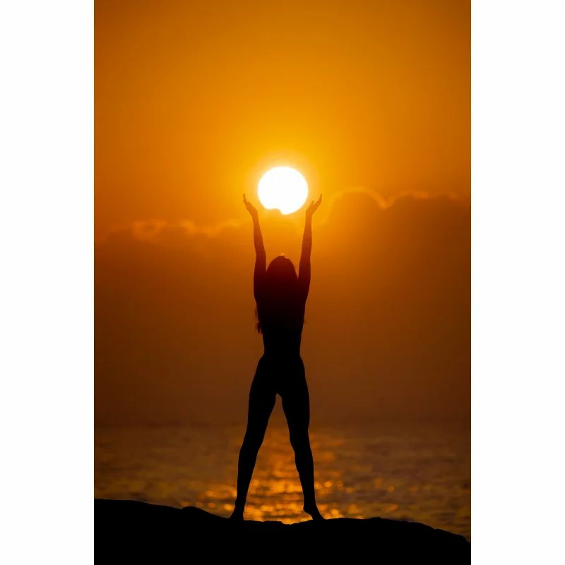 Silhouette einer Person, die die Sonne am Strand umarmt. Person mit erhobenen Armen. Hintergrund: Meer und Sonne.
