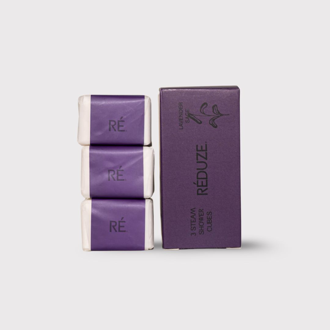 Drei Duschwürfel in Papier verpackt, neben einer lila Schachtel mit RÉDUZE-Logo.