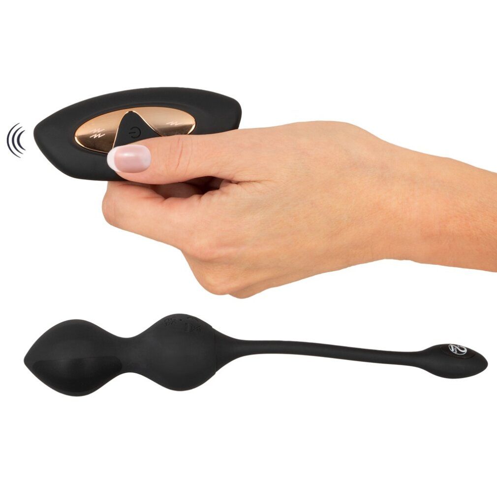 Hand hält Fernbedienung. Schwarz, längliches Produkt daneben.