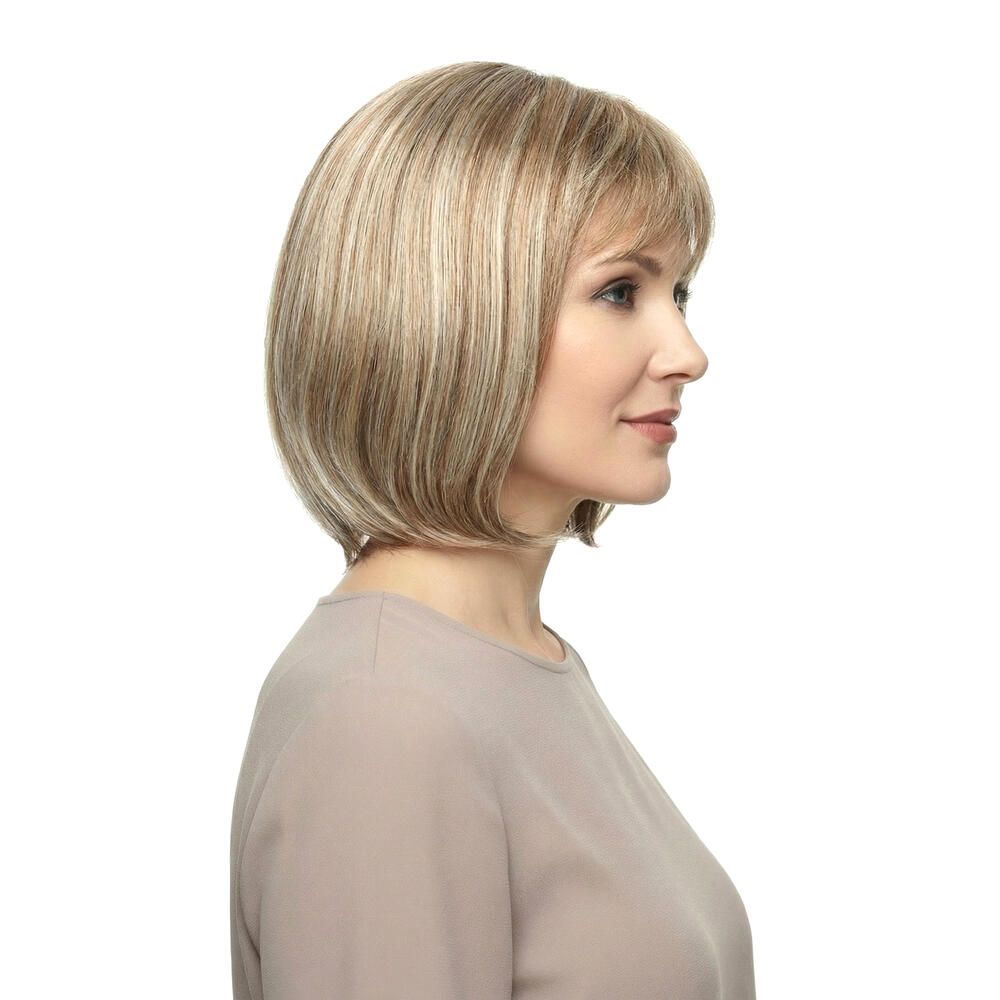 Perücke mit kurzem, blondem Haar und Pony. Die Frau trägt ein beiges Oberteil. Seitenansicht.