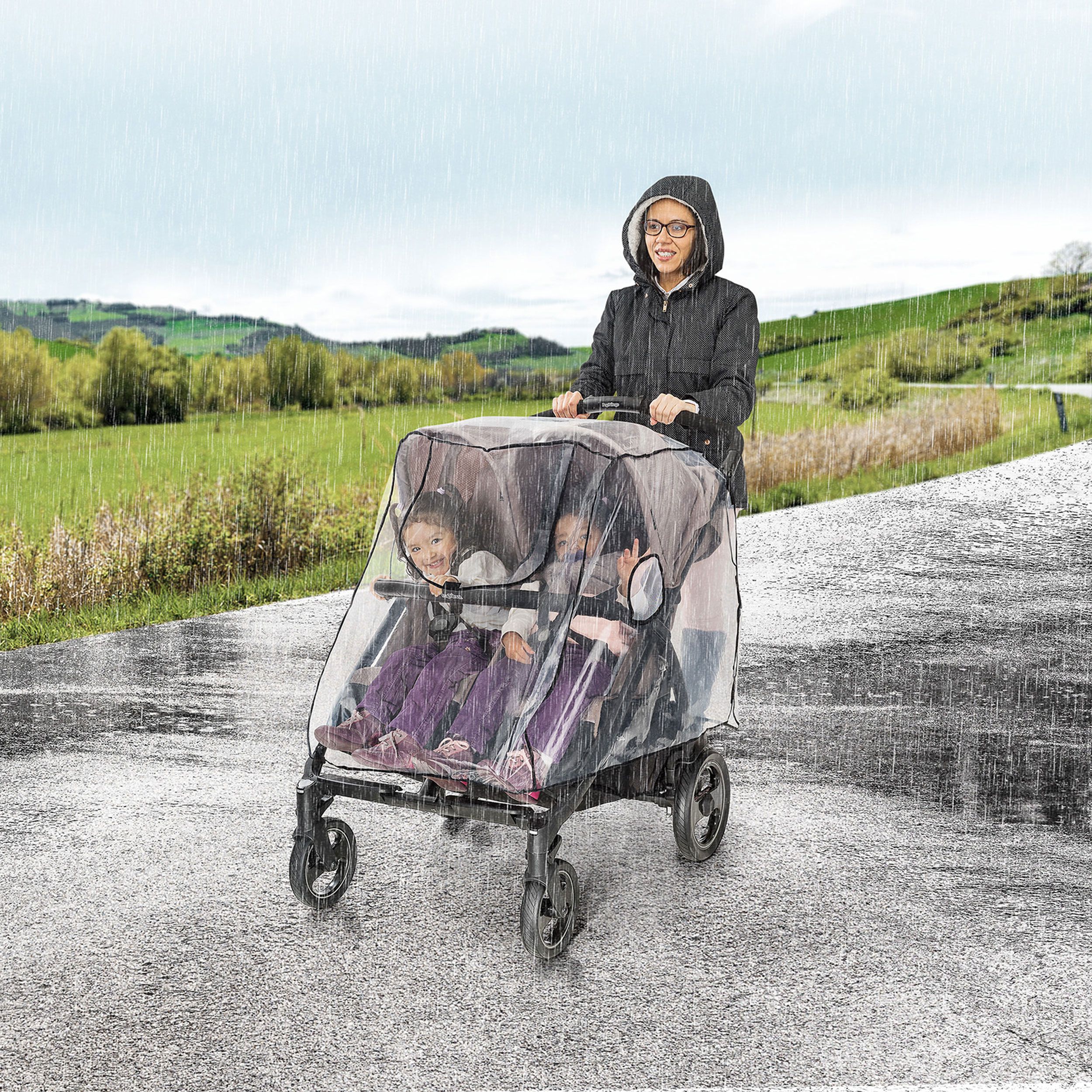 Zwillingskinderwagen mit Regenschutz im Regen. Person schiebt den Wagen.