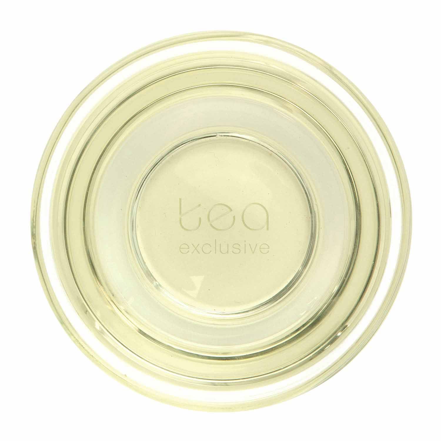 Glas mit gelblichem Getränk. Aufschrift "tea exclusive" am Boden des Glases. Draufsicht.