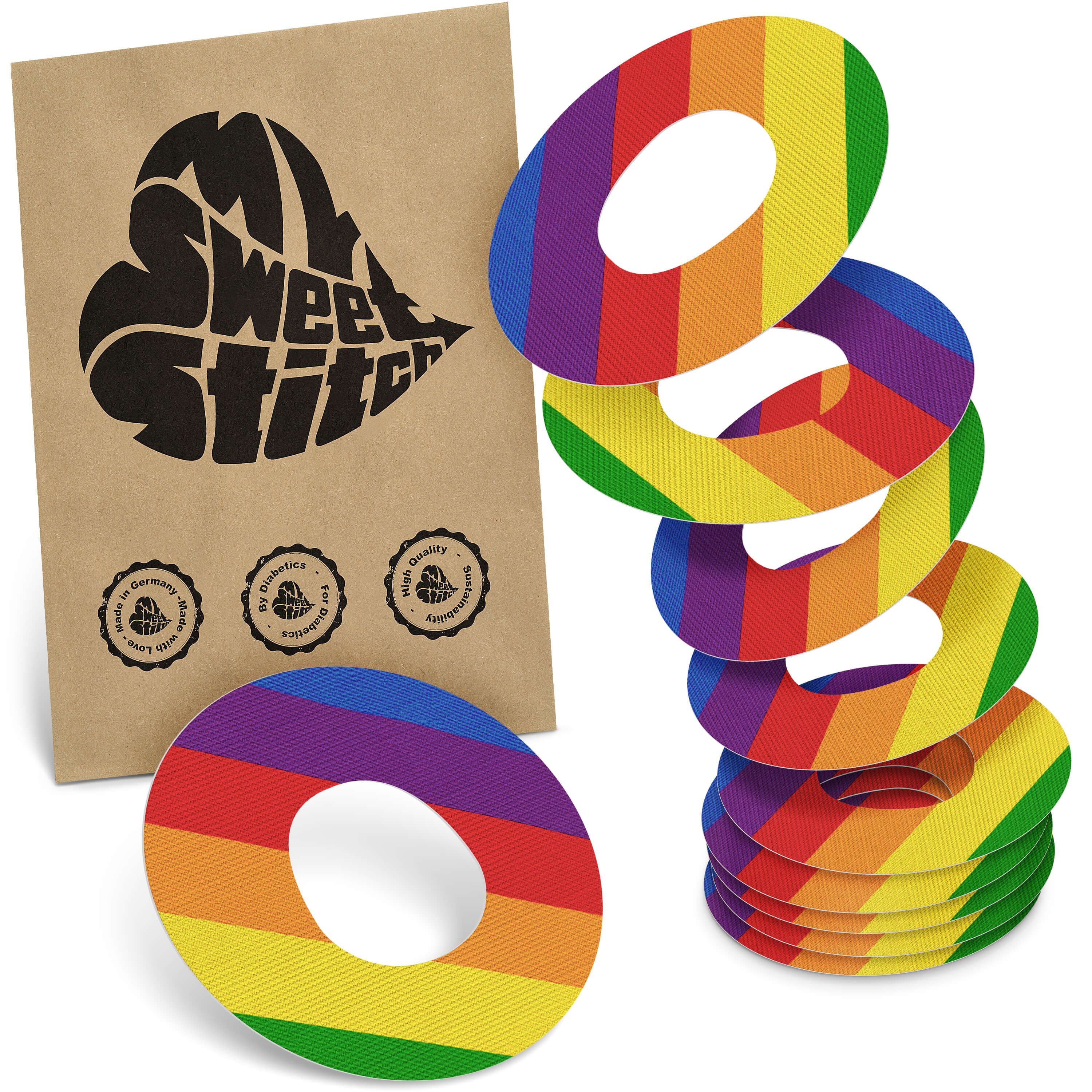 Fixierpflaster mit Regenbogenmuster. Ovale Form mit Loch in der Mitte. Braune Verpackung mit Logo.