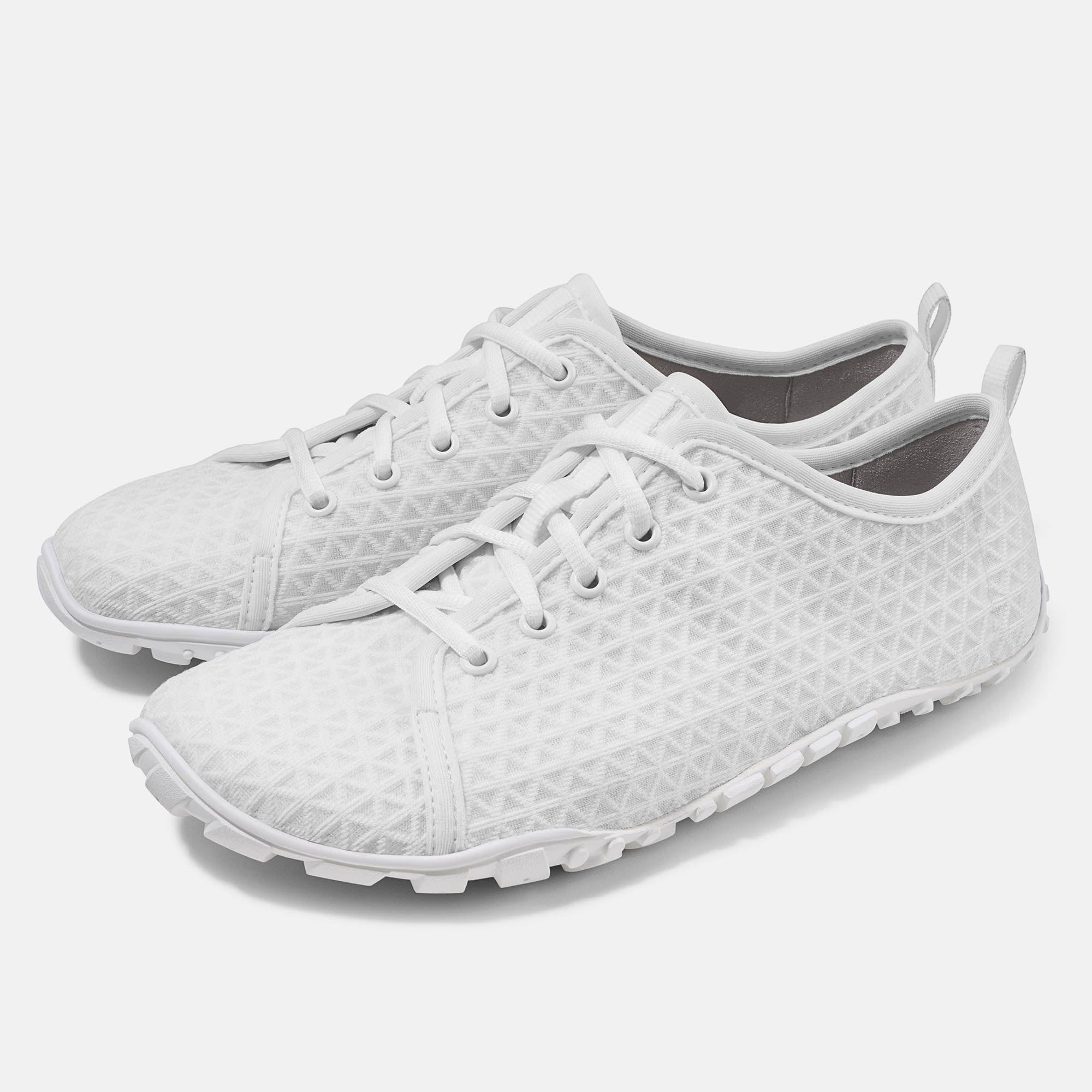 Zwei weiße Schnürschuhe mit geometrischem Muster. Breite Passform. Hellgrauer Hintergrund.