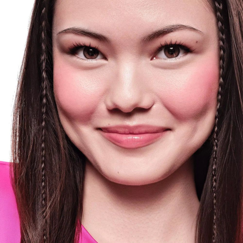 Porträt einer Frau mit Rouge auf den Wangen. Lange, dunkle Haare. Keine Verpackung sichtbar.