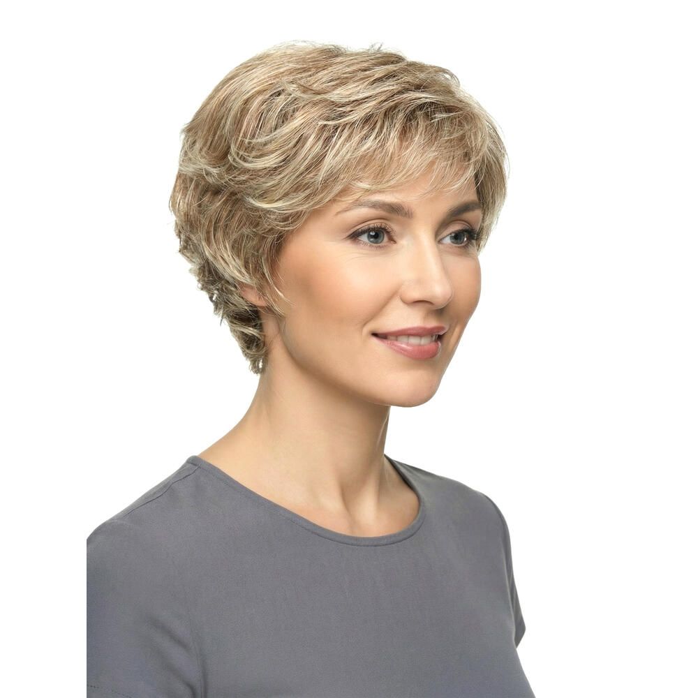 Perücke Iris von Lofty. Kurze, blonde Kunsthaarperücke mit gewellter Struktur. Frau trägt graues Oberteil. Dreiviertelansicht.