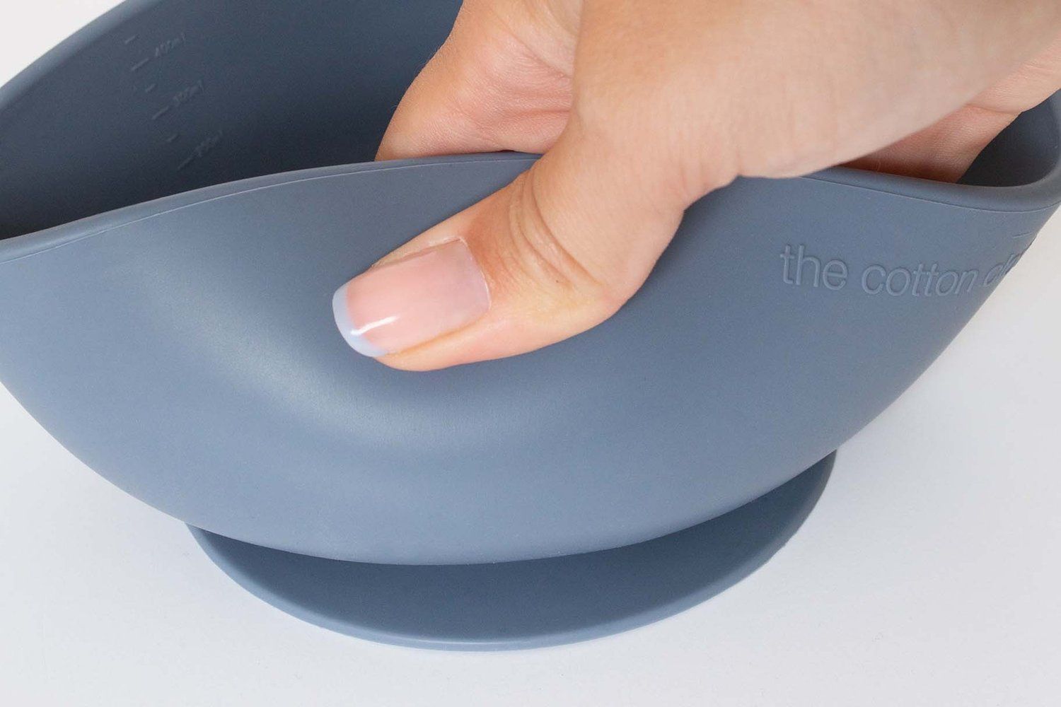 Blaue Schüssel mit Griff. Hand greift die Schüssel. Aufkleber auf der Unterseite.