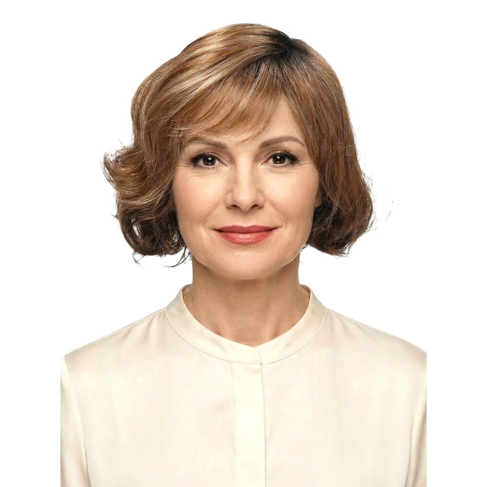 Frau mit brauner Perücke mit Pony. Die Perücke hat blonde Strähnen und welliges Haar. Sie trägt ein weißes Hemd.