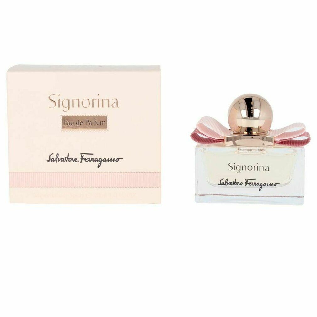 Signorina Eau de Parfum Spray. Rechteckiger Glasflakon mit rosa Flüssigkeit, rosa Schleife und goldfarbenem Verschluss. Verpackung daneben.
