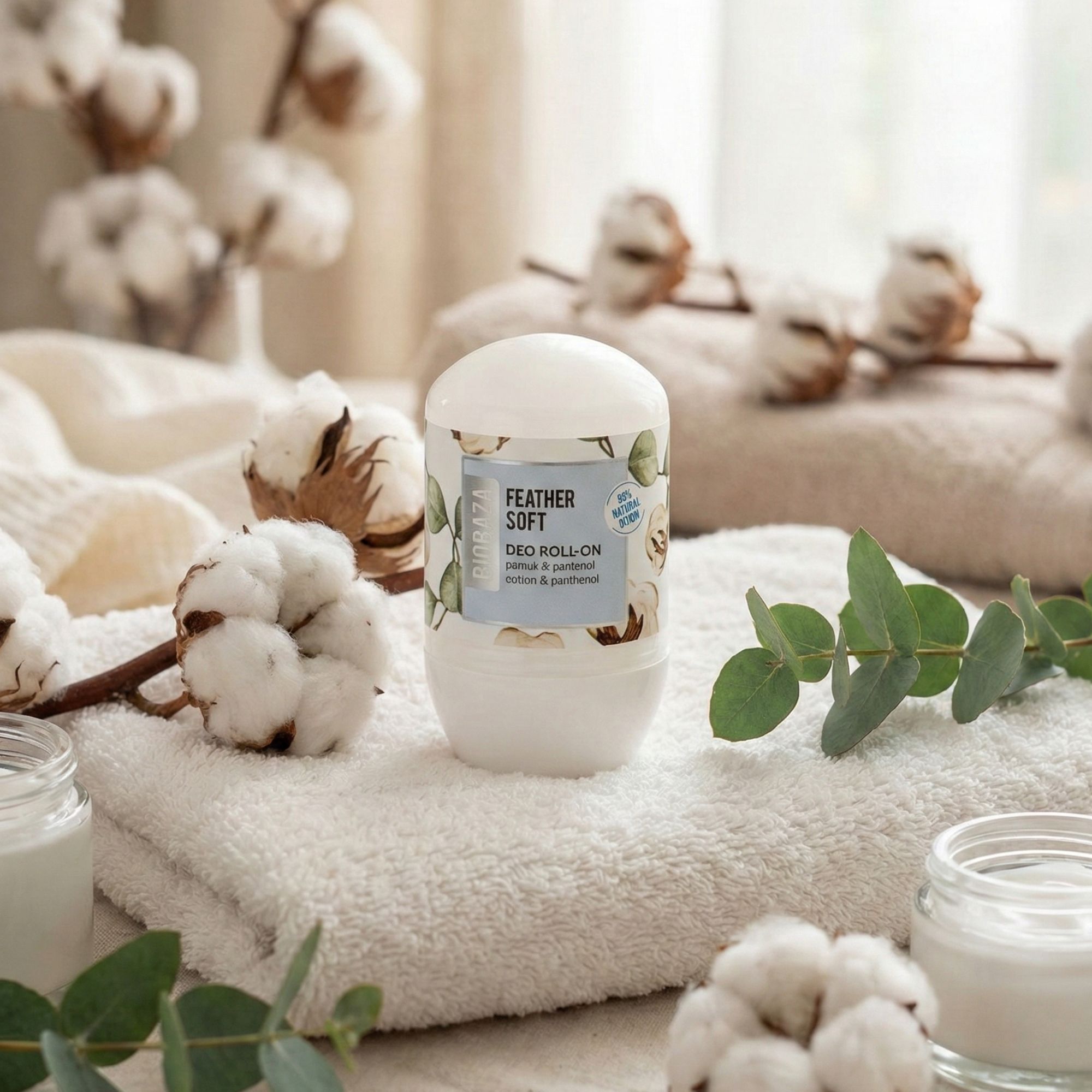 Weißer Deo Roll-On mit Etikett. Baumwollblüten und Handtuch im Hintergrund. Aufschrift: Feather Soft, Deo Roll-On.