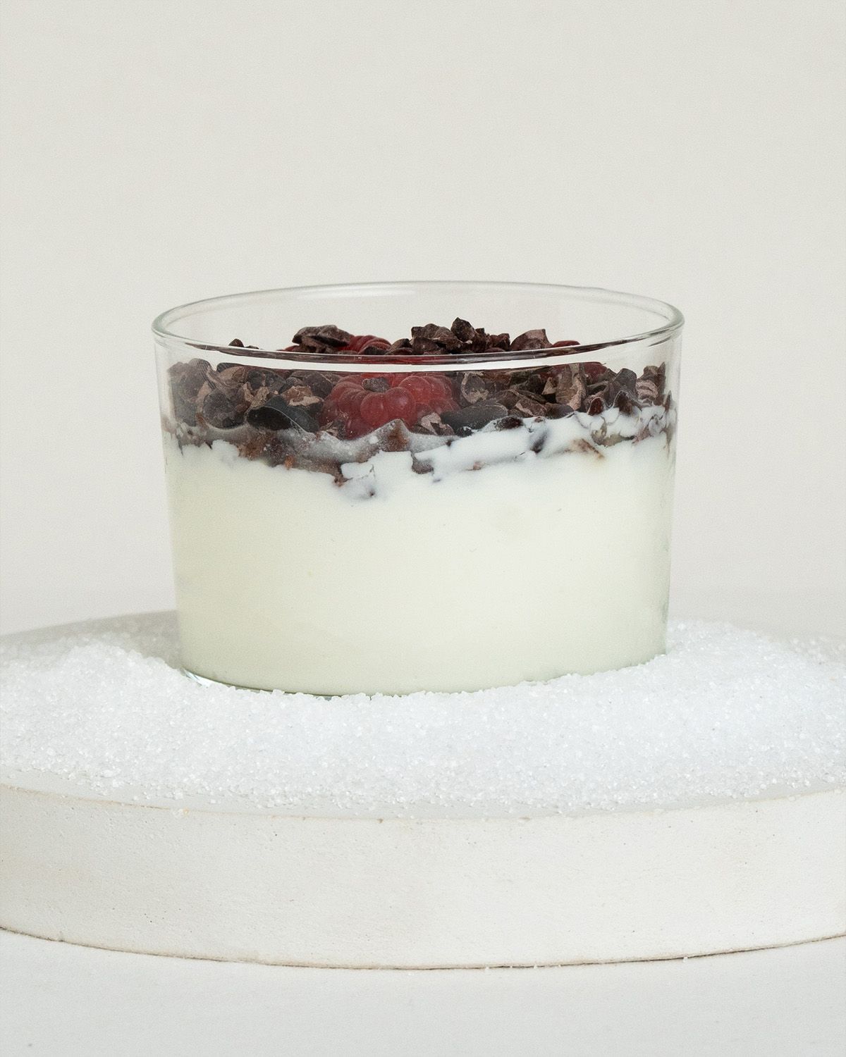 Glas mit Joghurt, garniert mit Beeren und Kakaonibs.