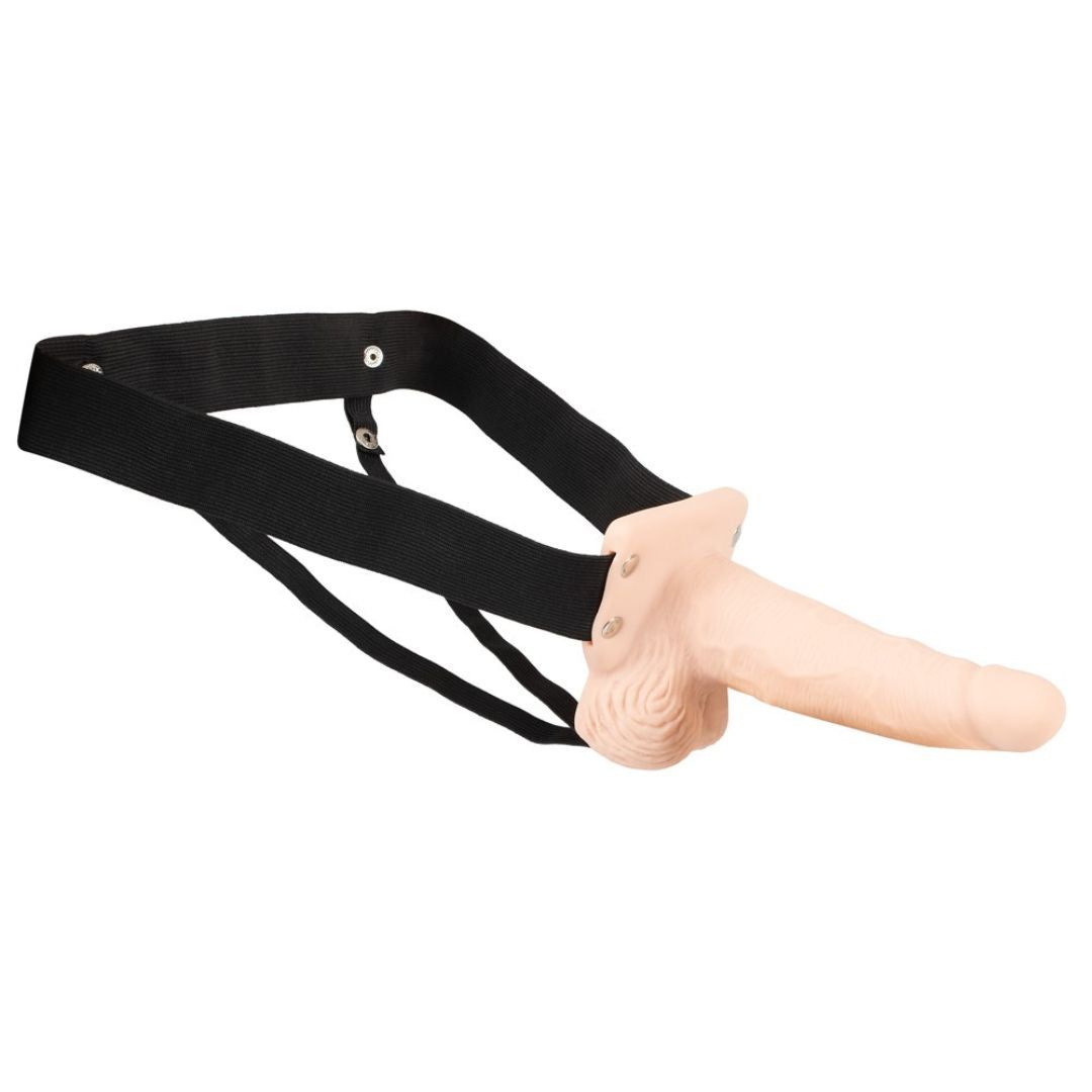 Beiger Dildo an schwarzem Strap-On-Gurt befestigt. Gurt mit Druckknöpfen. Dildo mit geriffelter Oberfläche.